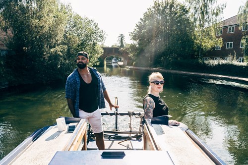 image of a couple steering a narrowboat on a canal