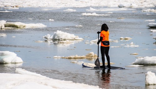 woman winter paddle boarding in ice