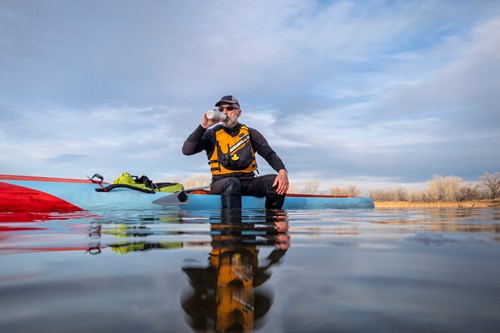 man drinking water whilst paddle boarding